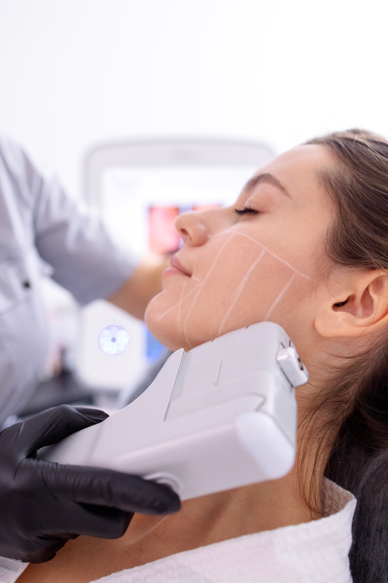 Portrait of relaxed young female client getting SMAS ultrasound face lifting massage
